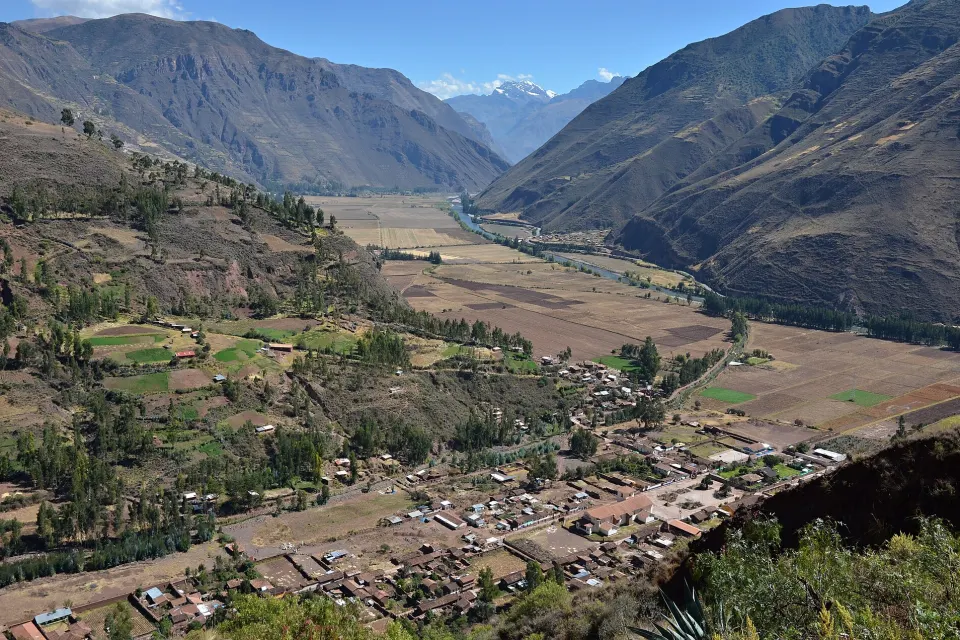 O Vale Sagrado dos Incas visto do alto de Taray, perto de Pisac, com o rio Vilcanota entre plantações e uma montanha nevada ao fundo