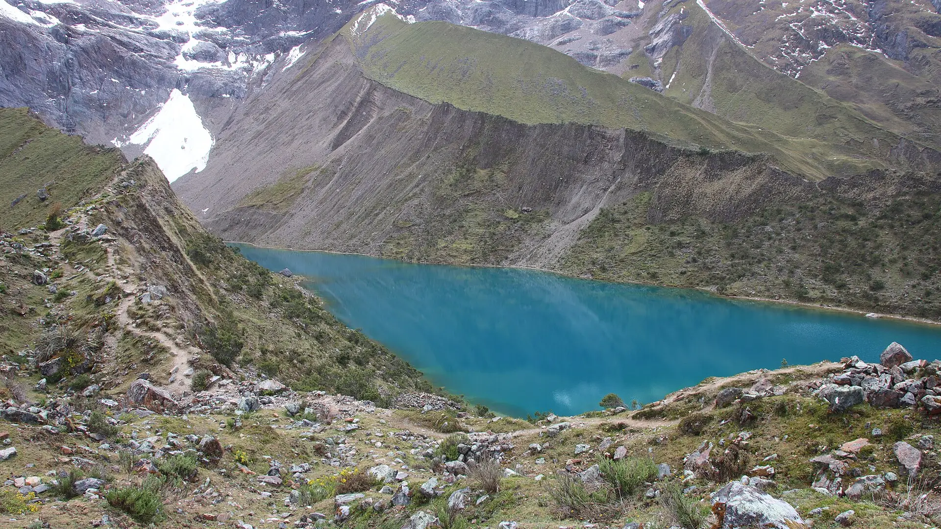 A Lagoa Humantay, de água azul-turquesa, ao pé do pico nevado Humantay, com a trilha de subida à esquerda