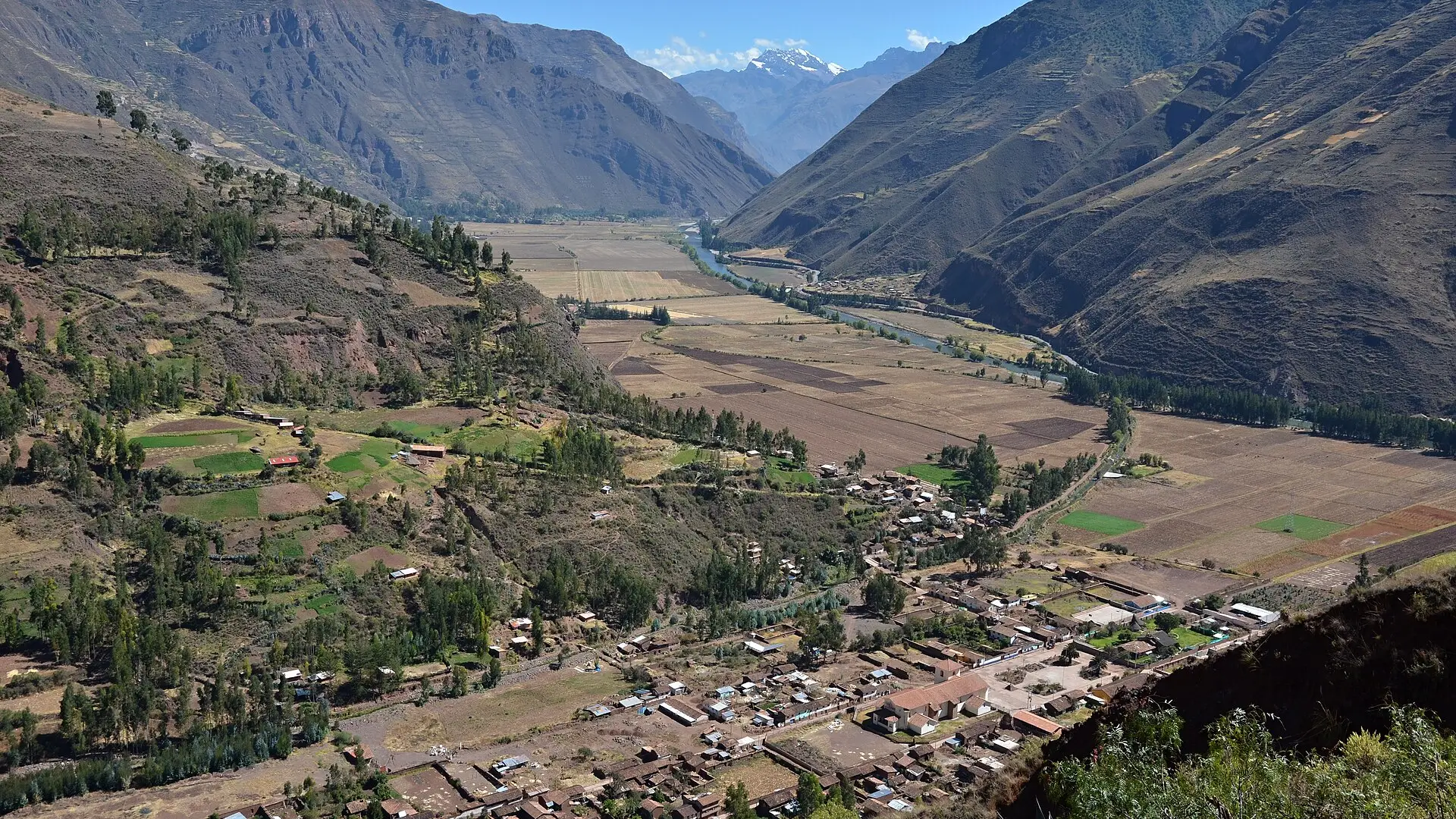 O Vale Sagrado dos Incas visto do alto de Taray, perto de Pisac, com o rio Vilcanota entre plantações e uma montanha nevada ao fundo
