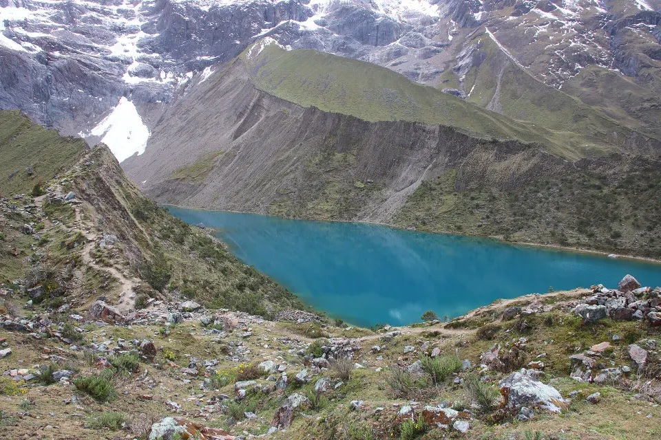 A Lagoa Humantay, de água azul-turquesa, ao pé do pico nevado Humantay, com a trilha de subida à esquerda