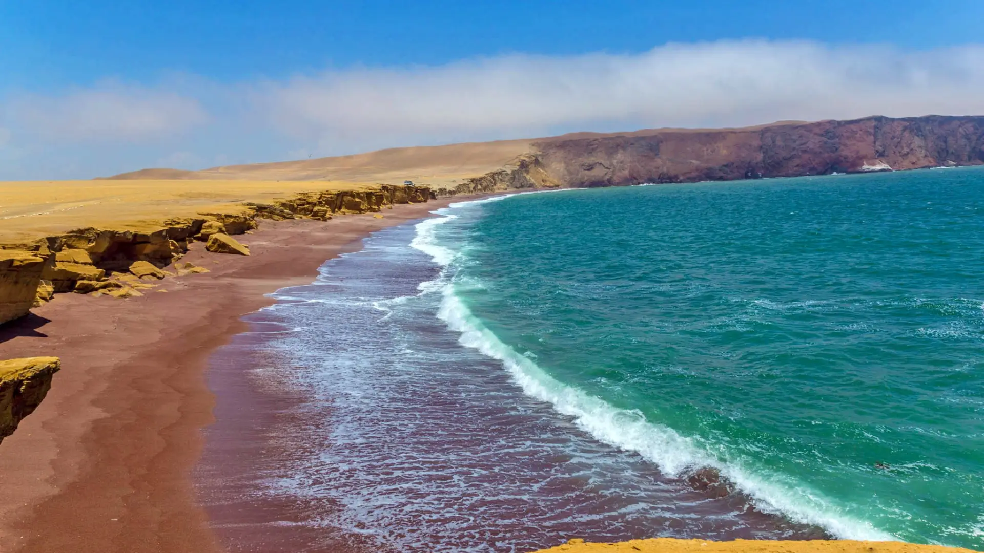 Playa Roja en la Reserva Nacional de Paracas: arena rojiza, mar turquesa y acantilados del desierto